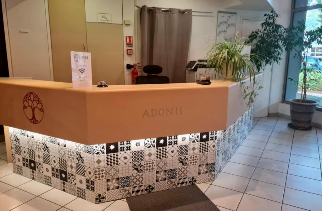 un comptoir d'accueil dans une pièce avec un sol carrelé dans l'établissement Adonis Gapotel, à Gap