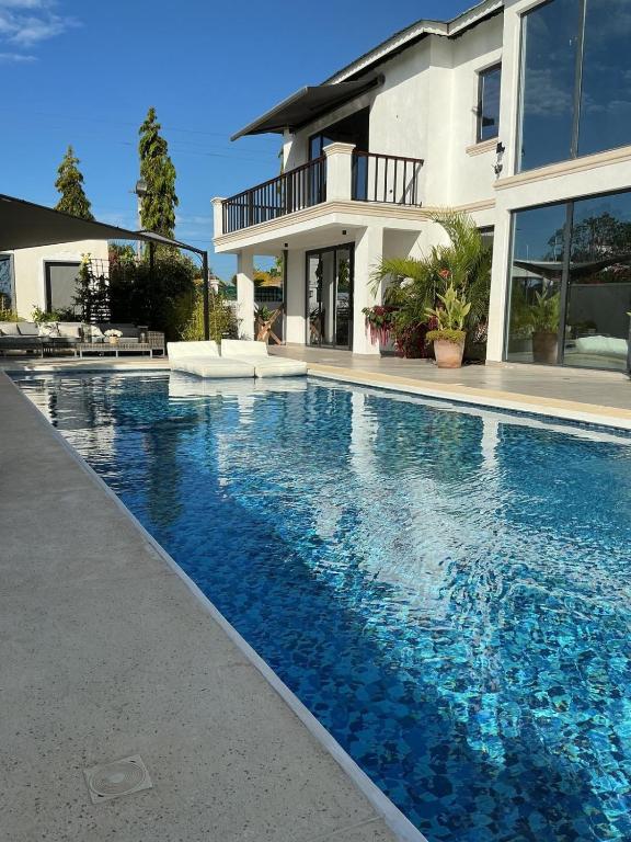 a large swimming pool in front of a house at Lulu Diani in Diani Beach