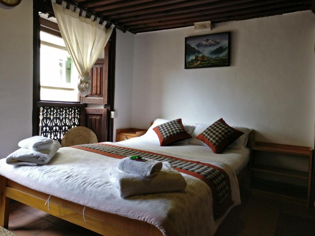 Hiranya Guest House في باتان: غرفة نوم عليها سرير وفوط