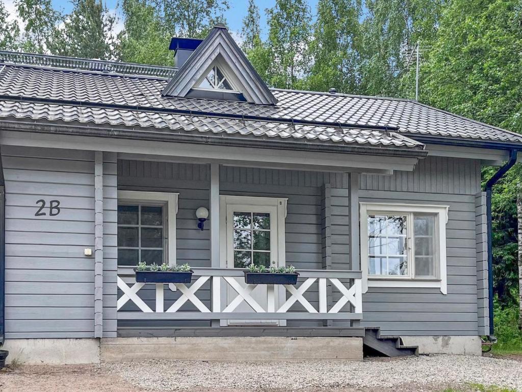 a small gray house with two windows and two potted plants at Holiday Home Sini 2b by Interhome in Lahdenperä