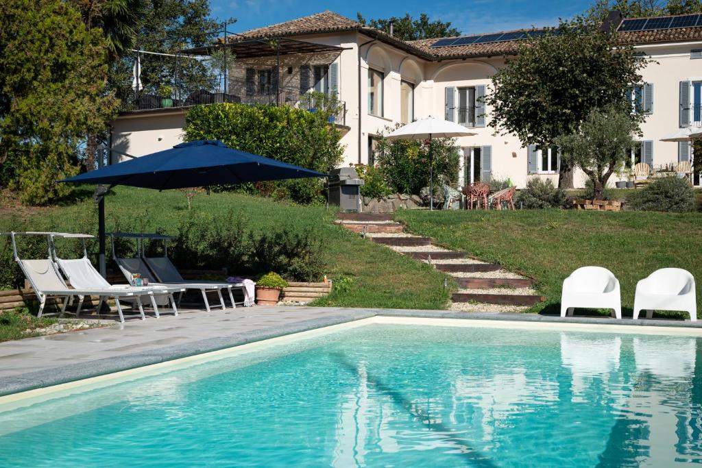 a house with a swimming pool with chairs and an umbrella at Tenuta Dei Vicini - Luxury Apartments in San Marzano Oliveto
