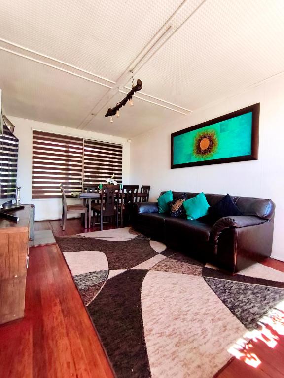 a living room with a black leather couch and a table at Hospedaje Luna in Valdivia