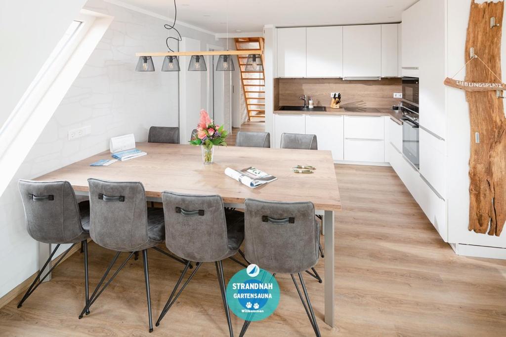 a kitchen and dining room with a wooden table and chairs at Winkelschiffchen IV mit Sauna in Juist