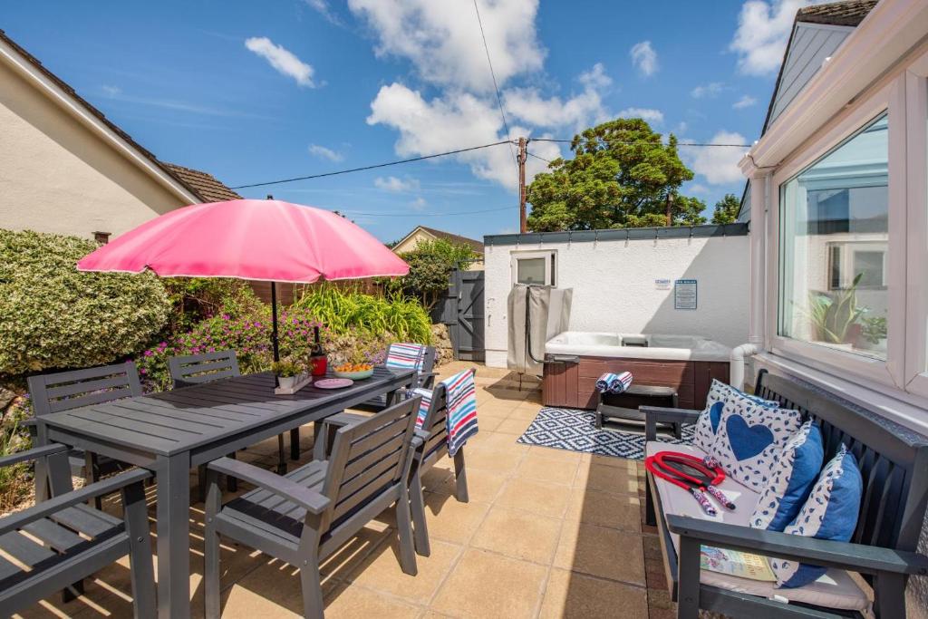 a patio with a table and chairs with a pink umbrella at 3 Bed in Braunton oc-b29581 in Braunton