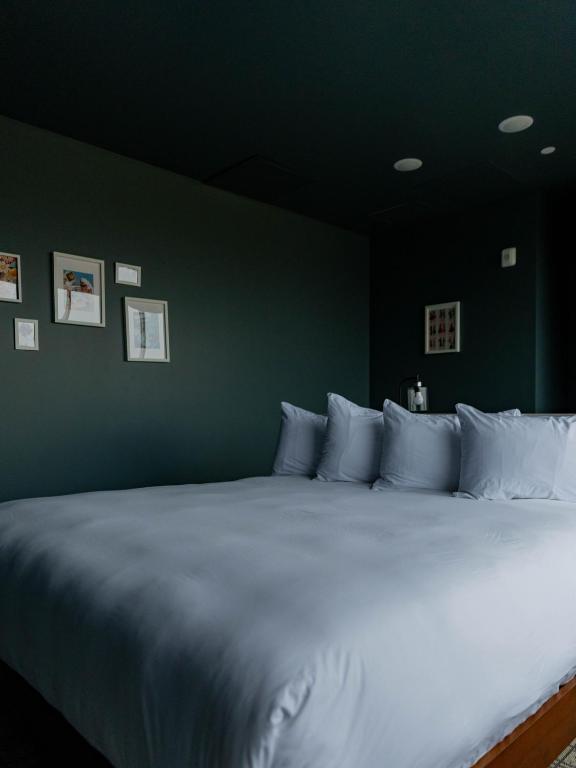 a bedroom with a large white bed with a green wall at Hotel Alexander in Mankato