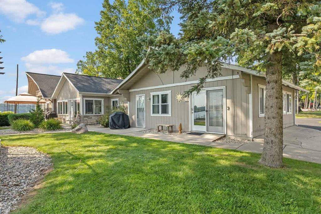 a house with a tree in the yard at 2 Lakefront Cottages with Docks, Bikes, BBQ in Newaygo