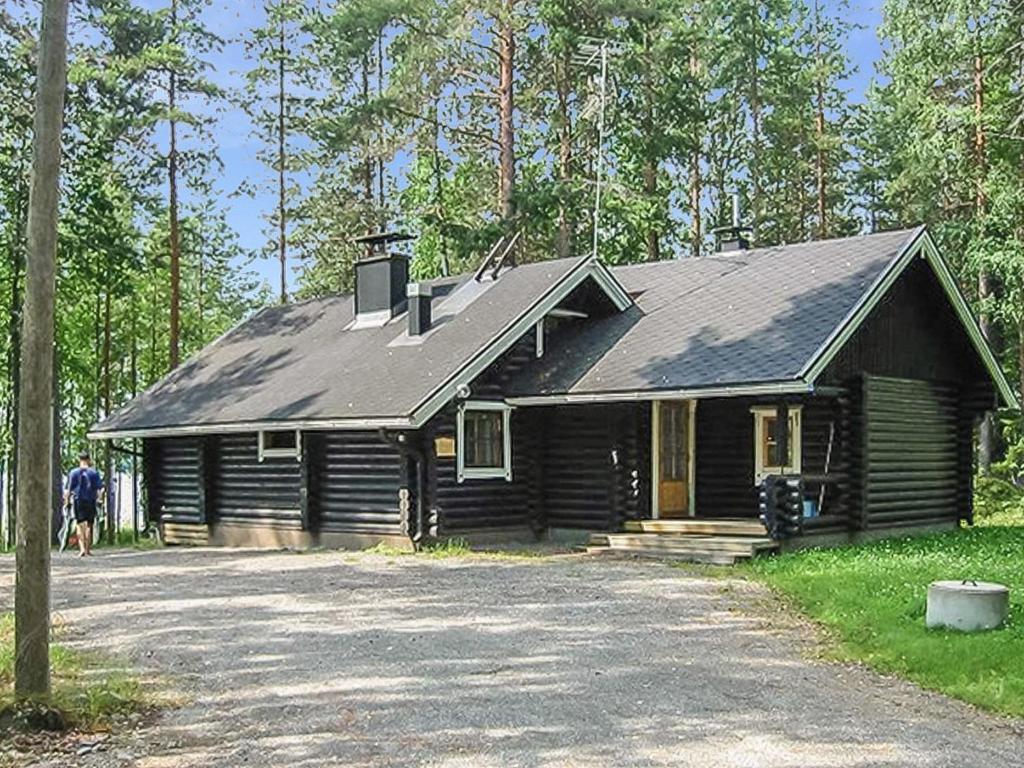 a log cabin with a man standing in front of it at Holiday Home Tavintupa by Interhome in Pertunmaa