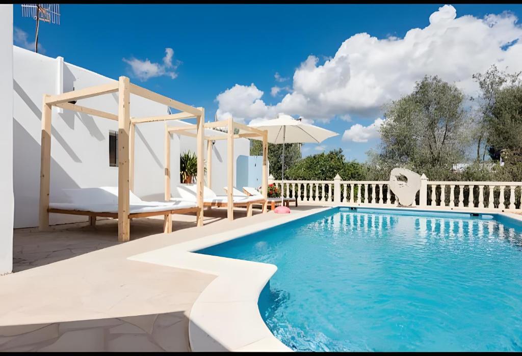 a pool with chairs and an umbrella next to a fence at Villa Can Marsa in Santa Eularia des Riu