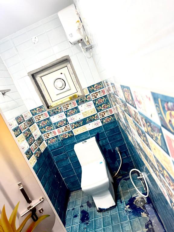 a bathroom with a toilet and a blue tiled wall at Santhosh hotel in Khammam
