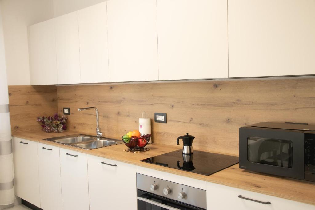 a kitchen with white cabinets and a sink and a microwave at Loft Giuliana in San Michele allʼAdige