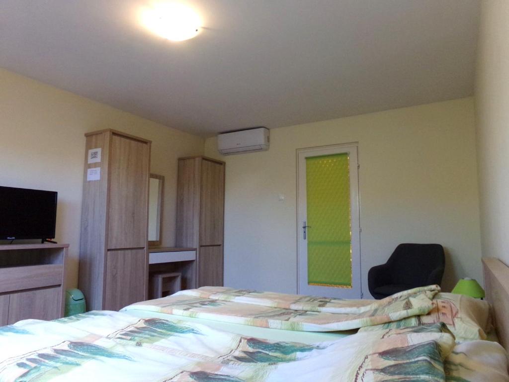 a bedroom with a bed and a chair and a television at Hold-on apartman in Gyula