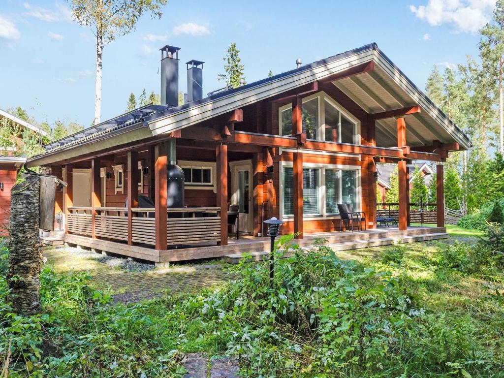 a house in the woods with a wrap around porch at Holiday Home Villa utu by Interhome in Kolinkylä
