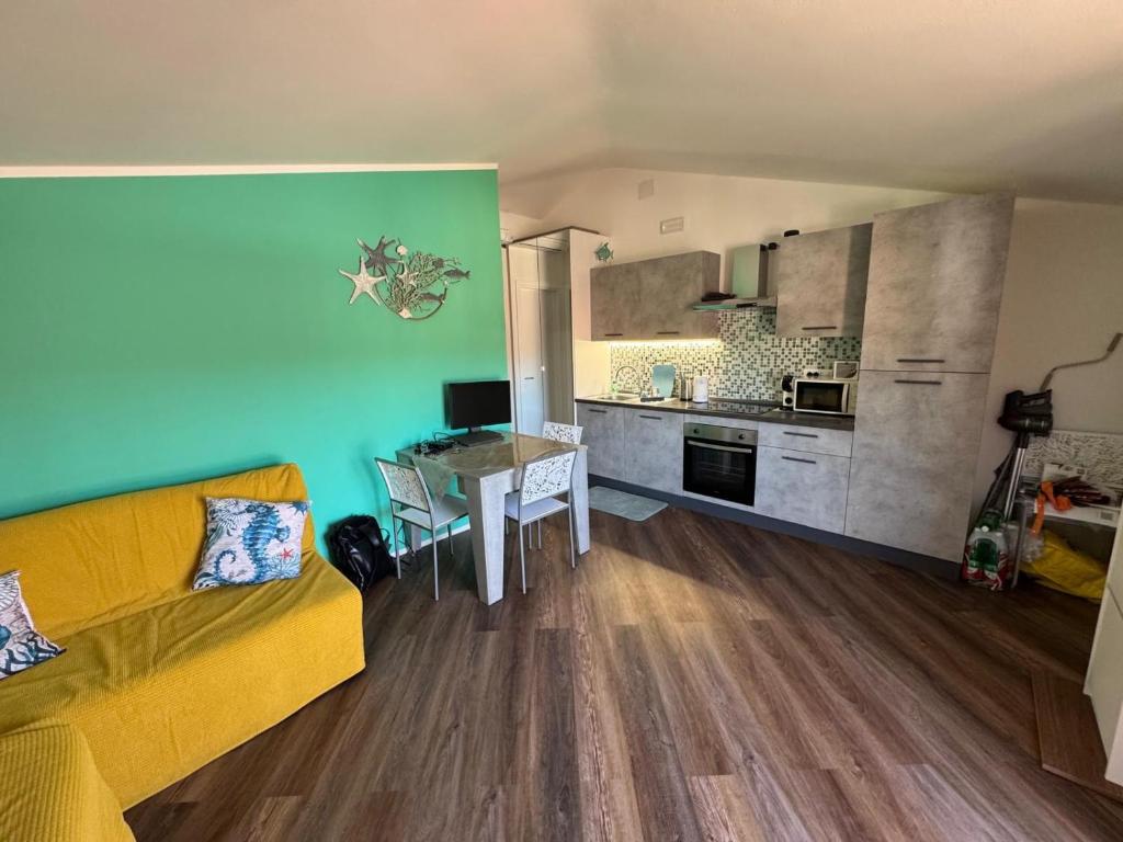a living room with a yellow couch and a kitchen at Attico Vicky in Porto Azzurro