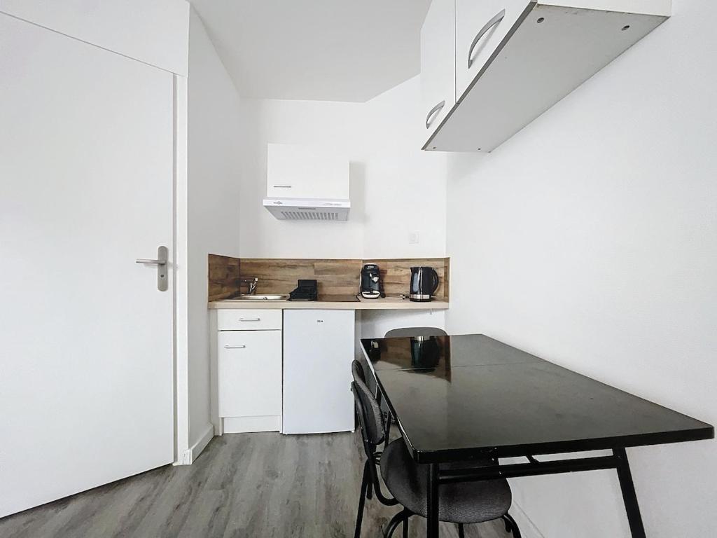 a kitchen with a black table and chairs in a room at Le Petit Jules in Dijon