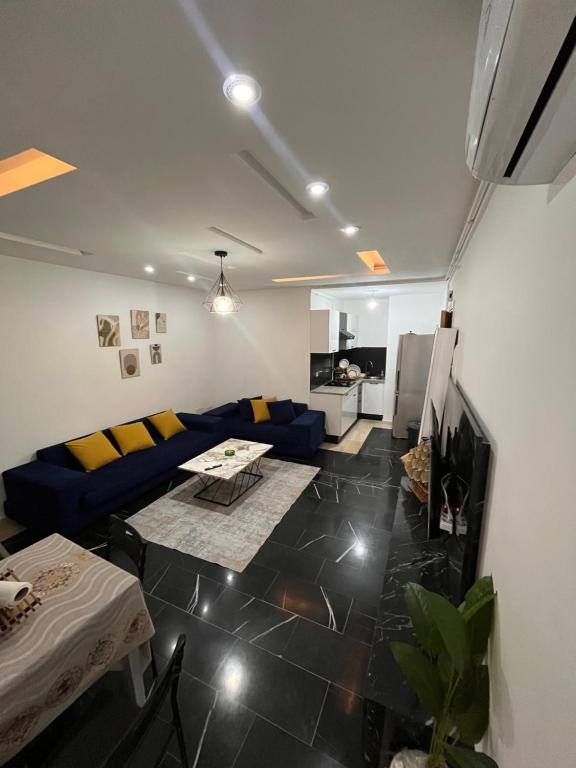 a living room with a blue couch and a table at Sweet homme in El Aouina Station