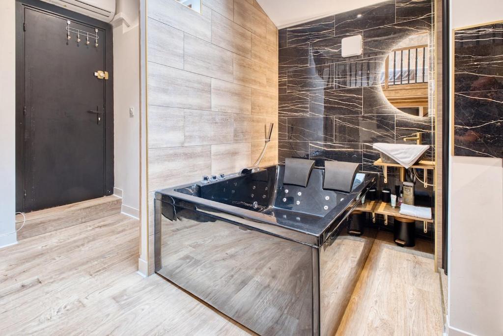 a bathroom with a black tub and a mirror at La bulle étoilée in Périgueux