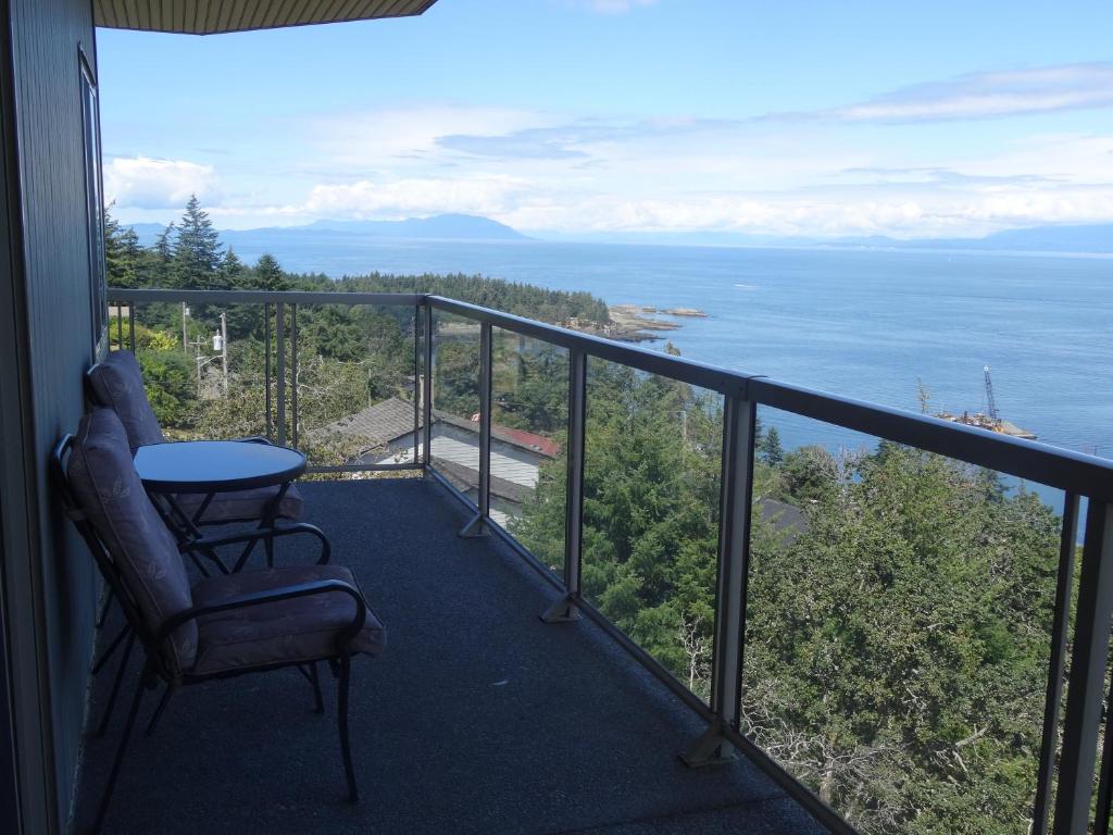 a balcony with a table and a chair and the ocean at Gibralter Rock Ocean View B&B in Nanaimo