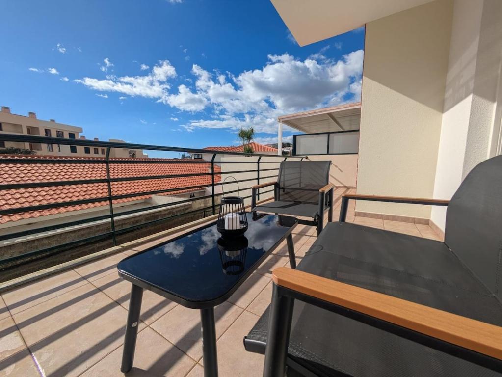 a balcony with a table and chairs on a roof at Pátio do Garajau Apartamento T2 com estacionamento e varanda perto do Cristo Rei in Caniço