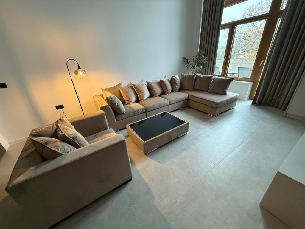 a living room with couches and a large window at Infinity Loft Residence in Târgu Jiu