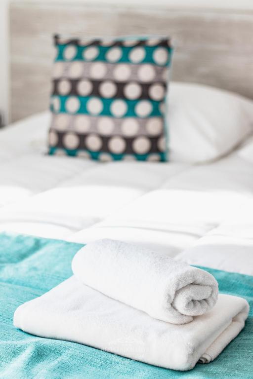 a pile of white towels on a bed with a pillow at Resplendor Hotel in Viña del Mar