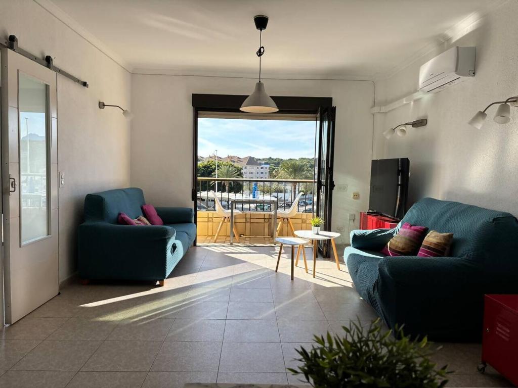 a living room with two blue couches and a balcony at Ap. con piscina, Moraira centro. in Moraira