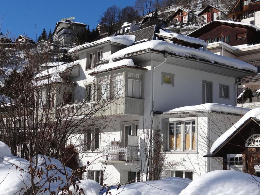 a white apartment building with snow on it at Apartment Bergfried by Interhome in Engelberg