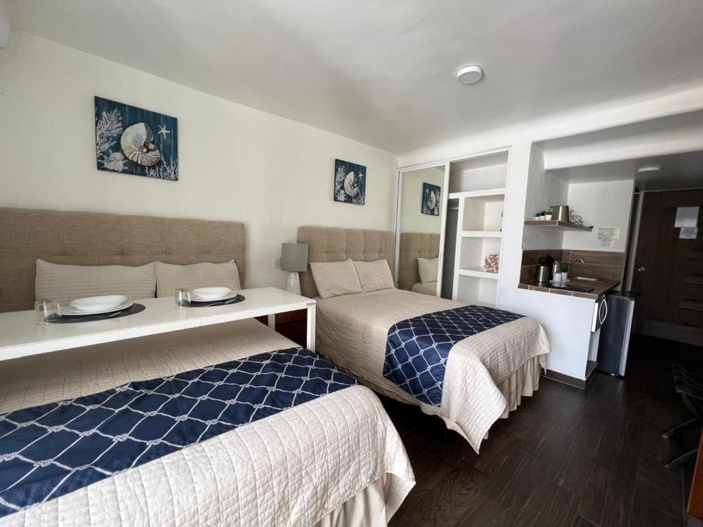 a hotel room with two beds and a table at SKY INN Oficial Acapulco Suites & Condo Mediterrane in Acapulco