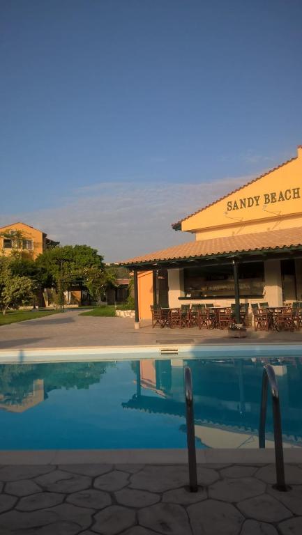 a swimming pool in front of a restaurant at Sandy Beach Villas and Apartments in Svoronata