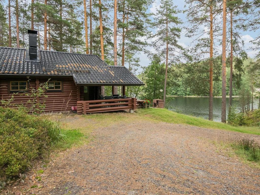 a log cabin with a porch next to a lake at Holiday Home Salmela by Interhome in Ollila