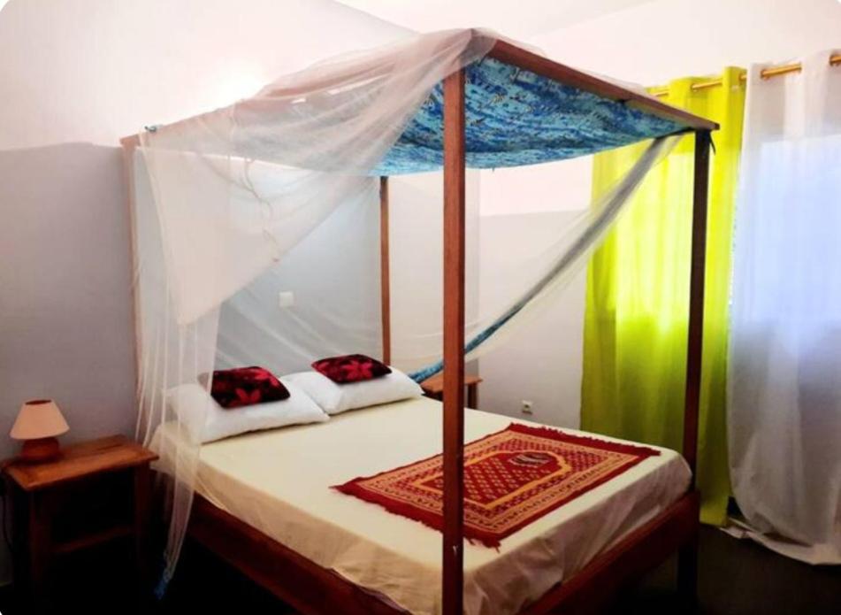 a bed with a canopy in a room at Villa AfricaSolly in Poponguine