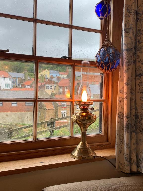 a candle in front of a window with a view at Old Jack's Cottage, Staithes in Staithes