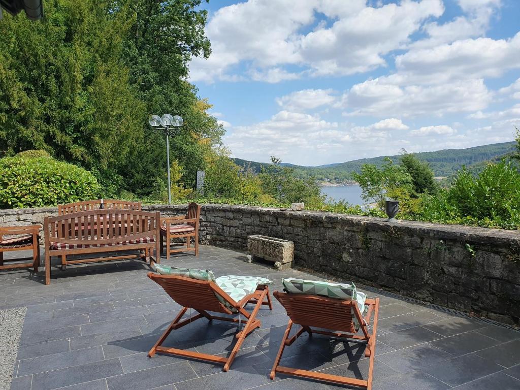 a patio with two chairs and a table and a stone wall at Ferienhaus am Rursee - Haus Eiche in Simmerath
