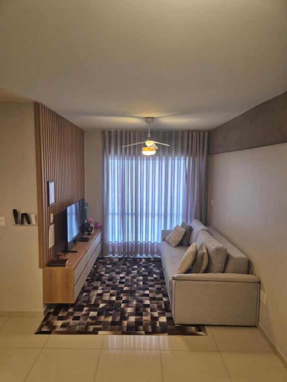 a living room with a couch and a television at Apartamento Amplo e Confortável em Condomínio Familiar, 3 Quartos Sendo 1 Suíte com Lazer de Clube in Belém