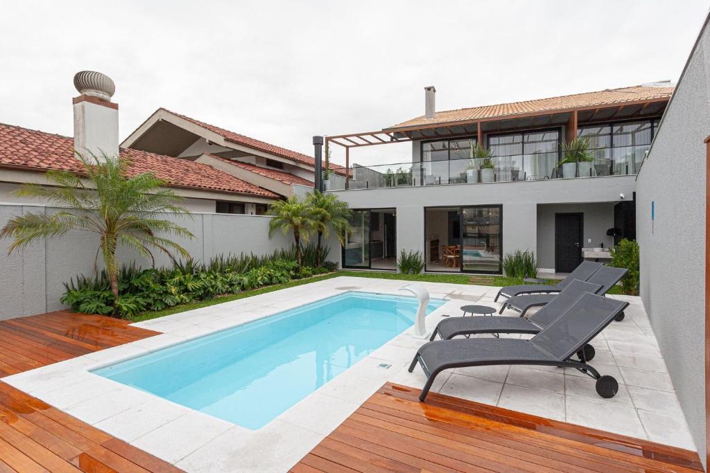 a house with a swimming pool and some chairs at Azurine Pousada in Passo de Torres