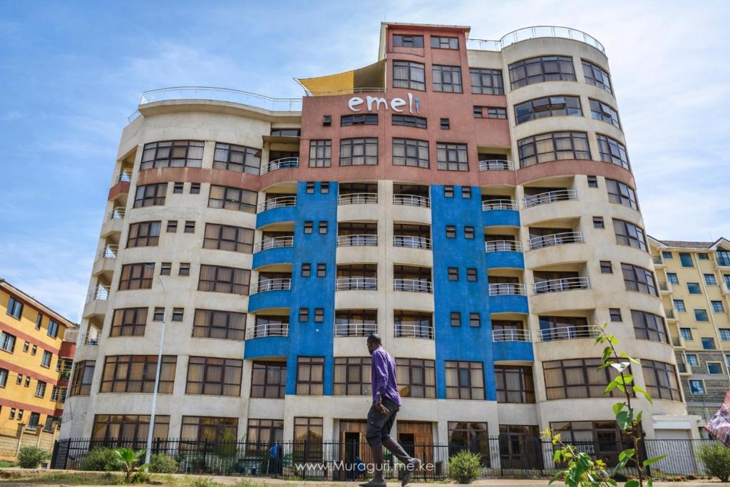 a man walking in front of a tall building at Mardley Suites in Nairobi
