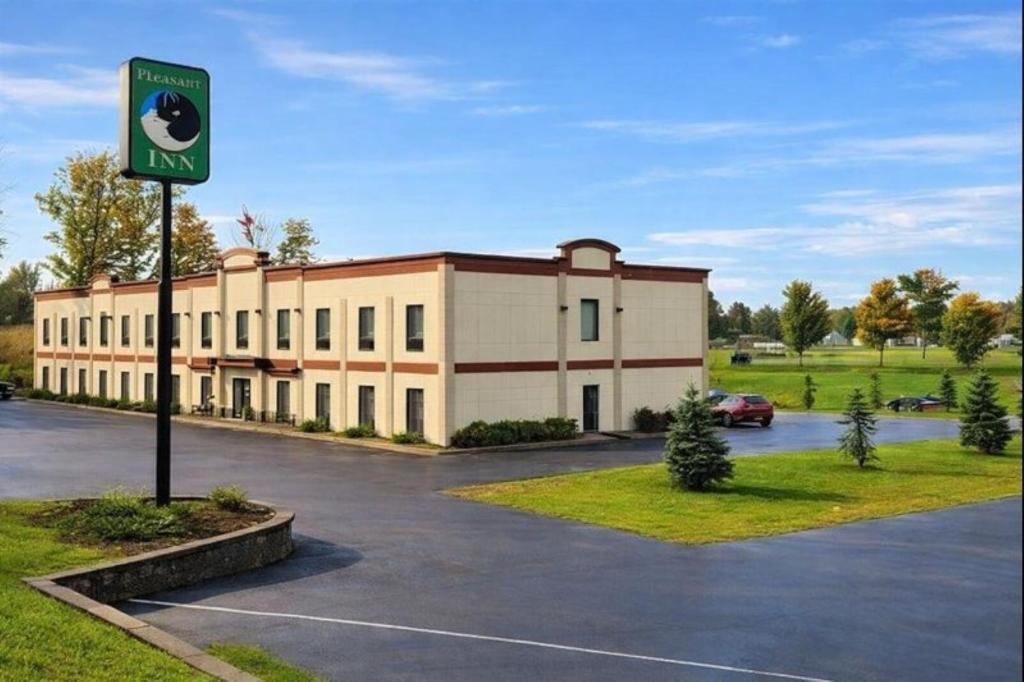 a building with a sign in a parking lot at Pleasant Night Inn Carthage Near Fort Drum in West Carthage