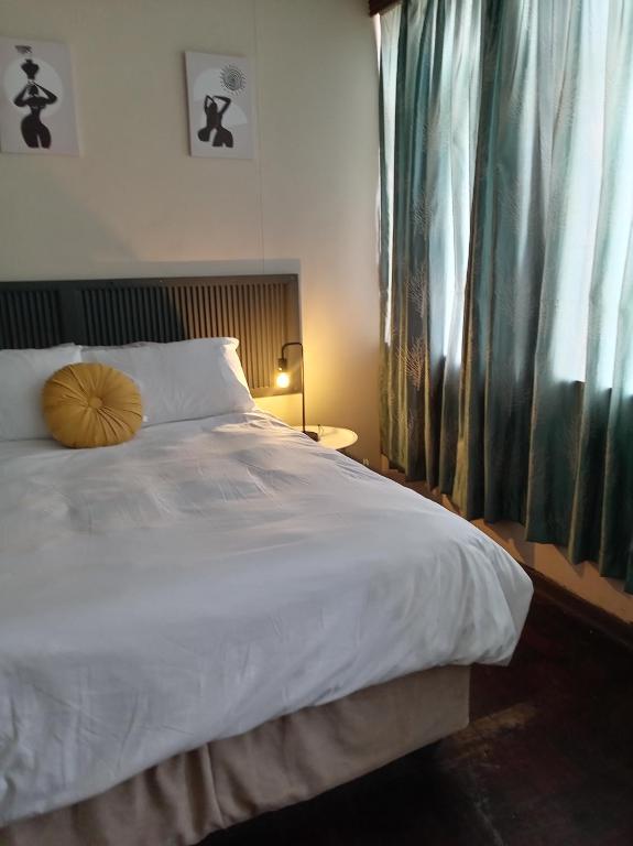 a bedroom with a large white bed and a window at Comfy spacious apartment in Pretoria