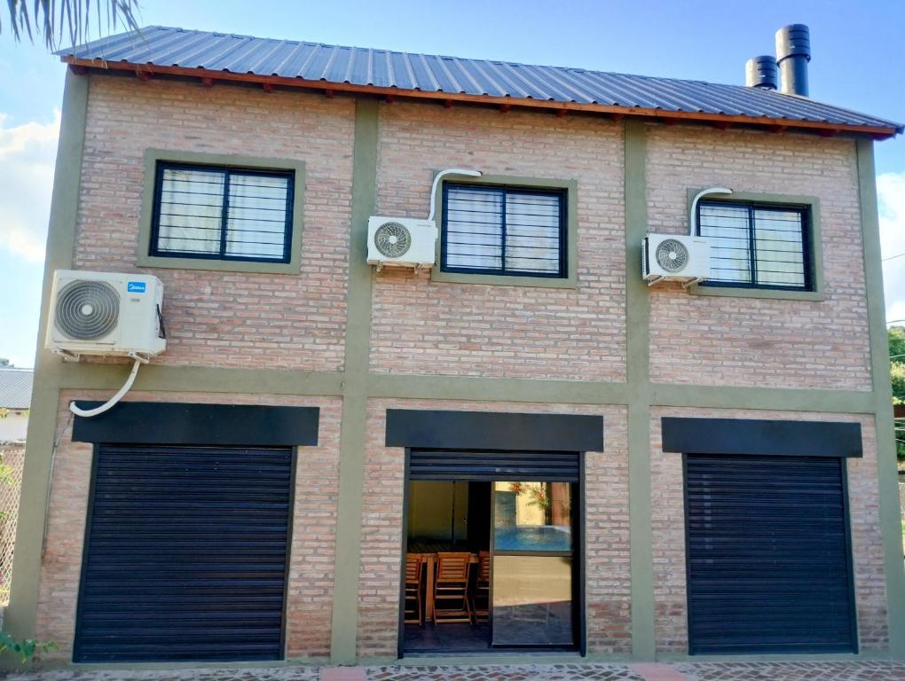 a brick building with two garage doors and two speakers at Casa Tapyí Paso in Paso de la Patria