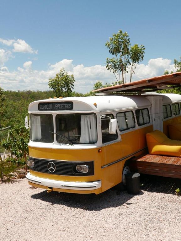a yellow and white van parked in a gravel lot at Refúgio Veadeiros Ônibus in Sao Jorge