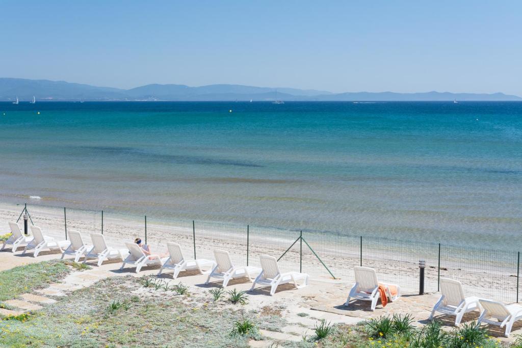 uma fila de cadeiras brancas na praia em Le Surplage em Hyères
