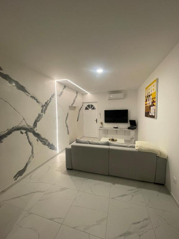 ein Wohnzimmer mit einer Couch und einem Fernseher an der Wand in der Unterkunft Station in Saint-Étienne-de-Saint-Geoirs
