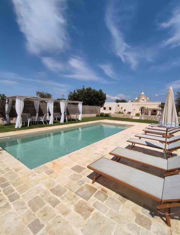 a swimming pool with lounge chairs and umbrellas at Domus Petri 1908 in Cisternino