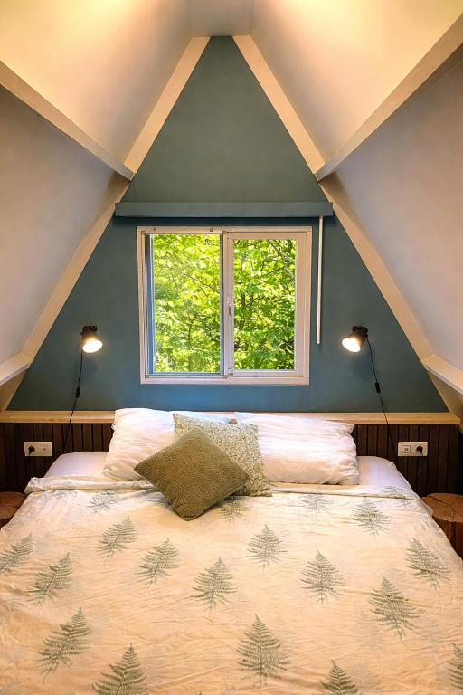 a bedroom with a large bed with a window at Chalet Tournesol Durbuy in Durbuy
