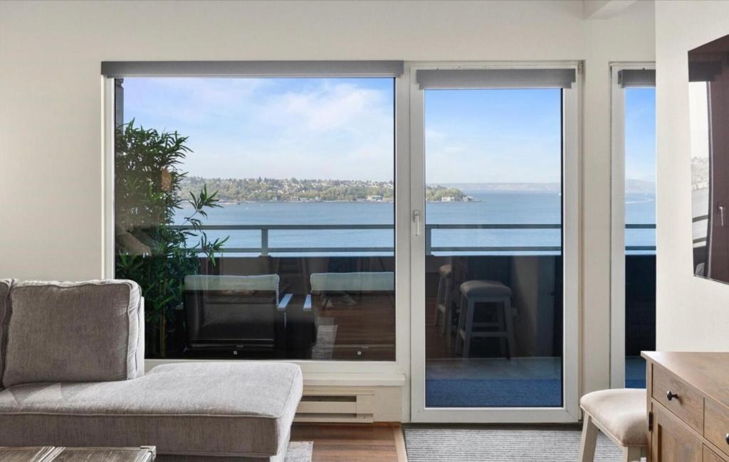 a living room with sliding glass doors with a view of the ocean at Luxury, ocean view Condo with deck and indoor pool in Seattle