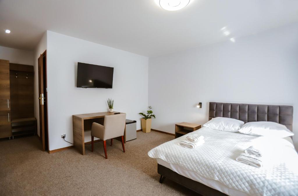 a bedroom with a bed and a desk and a tv at Hotel Lubaczów Hotel Restauracja u Dina in Lubaczów
