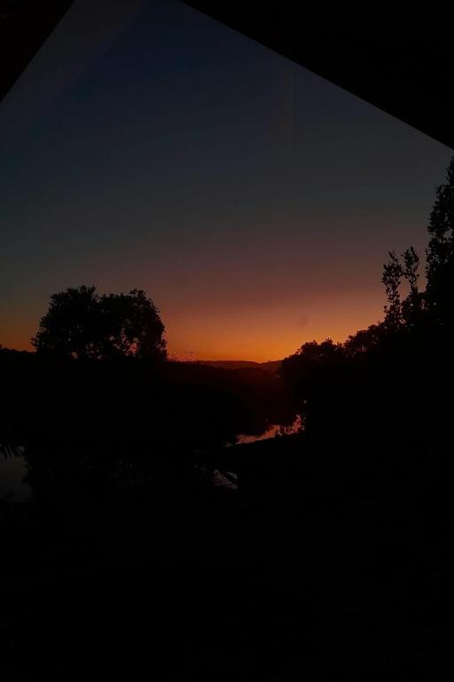 a sunset over a body of water with trees at RiverBanks in Wilderness