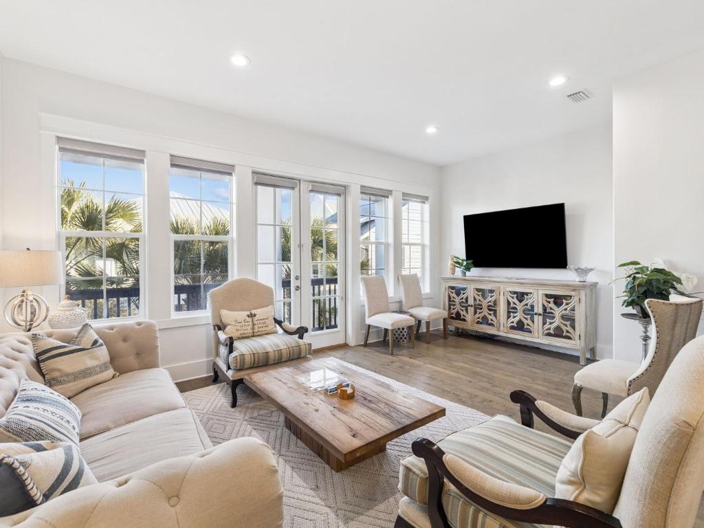 a living room with white furniture and a flat screen tv at CaSEAta by 30A Escapes in Rosemary Beach