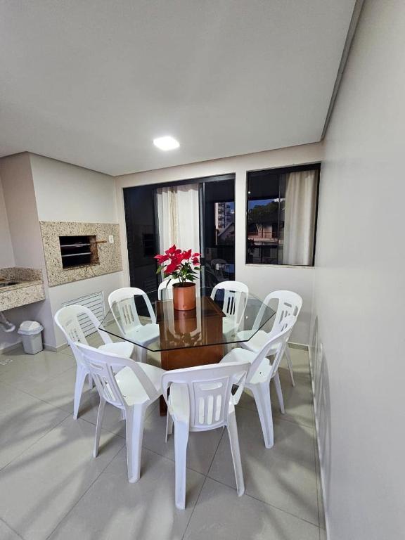 a dining room with a table and white chairs at Apartamento 3 Quartos - Centro de Piratuba in Piratuba