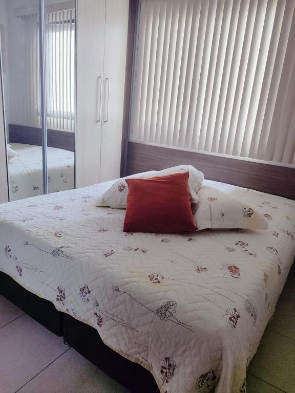 a bed with a red pillow on it in a bedroom at Apartamento Completo I Suíte Casal in Guarapari