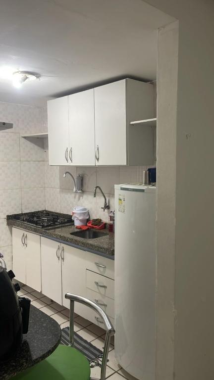 a kitchen with white cabinets and a refrigerator at Solares Residence in Teresina